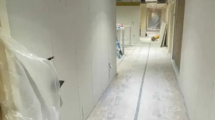 Plastic containment beside opened wall bottoms in a hallway during structural drying