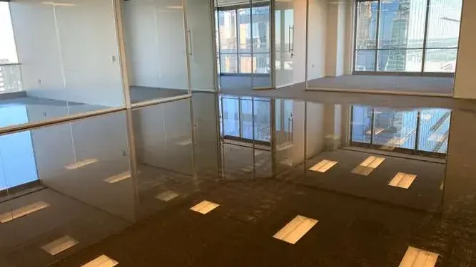 Standing water reflects windows across an open commercial room floor