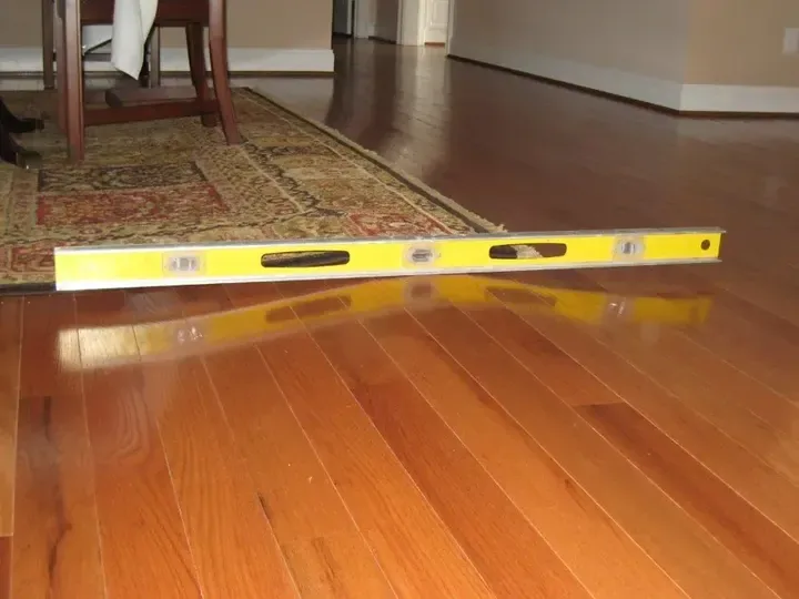 A level rests across cupped hardwood boards after water exposure